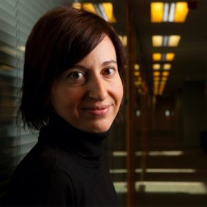 A woman in black shirt standing next to a wall.