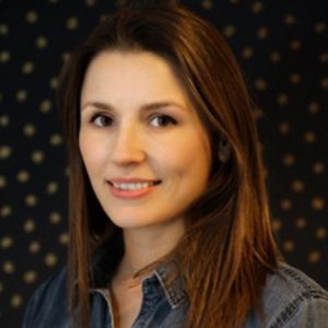 A woman with long brown hair wearing a blue shirt.