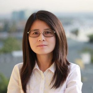 A woman with glasses and long hair wearing a white shirt.